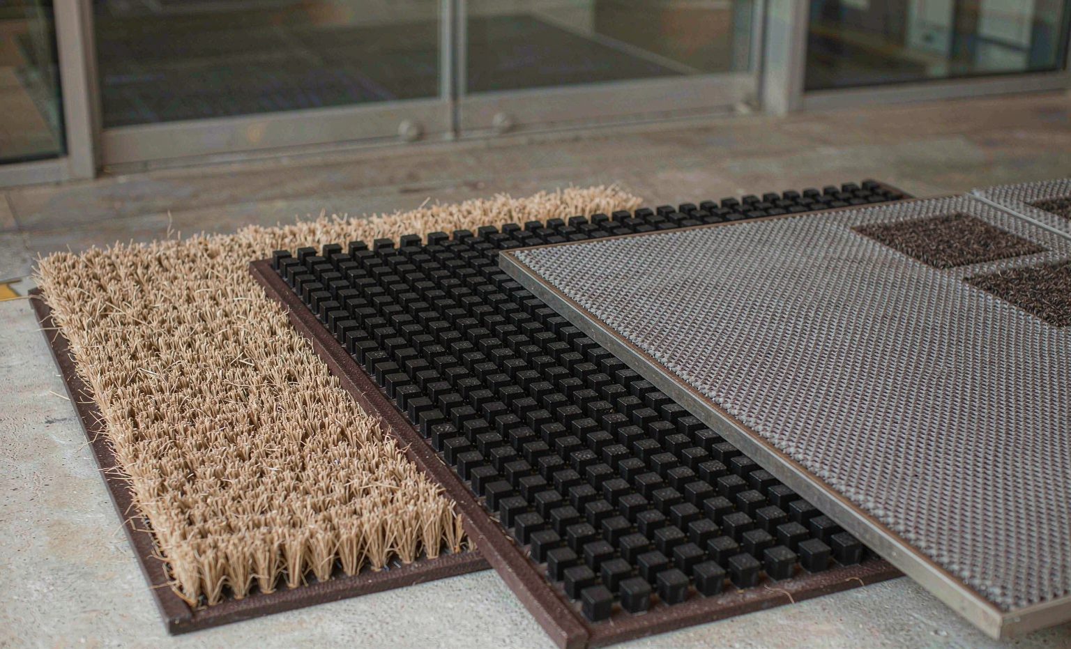 Coir, rubber and aluminium entrance mats laid side by side
