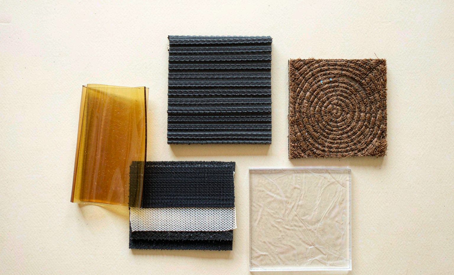 Grid of five material samples: amber PVC strip, grooved rubber mat, conveyor belt, coir matting and clear PVC sheet